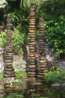 Säulenbrunnen aus Flusssteinen in Teich integriert